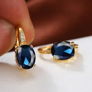 Makroaufnahme ovaler blauer Zirkonia-Ohrringe in Goldfassung mit Akzenten
