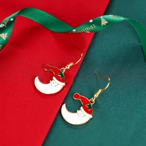 Macro detail of Christmas moon earrings with red Santa hat and green star accents