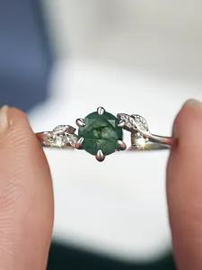 Detailed view of moss agate ring with silver leaf accents and round green gemstone