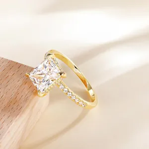 Golden rectangular princess cut zircon ring with four-prong setting on silk background