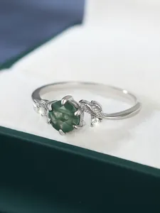 Macro shot of green moss agate ring with leaf-shaped silver band on velvet lining
