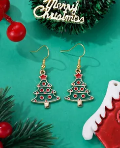 Detailed view of green Christmas tree drop earrings with red accents on festive background