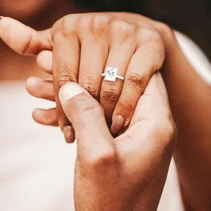Detail of a sparkling rectangle diamond engagement ring on a hand with soft lighting