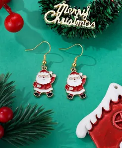 Detailed close-up of festive Santa Claus enamel hook earrings on a green holiday backdrop