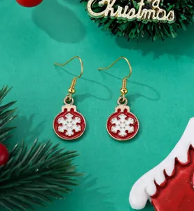 Close-up of red and gold Christmas ball earrings with 3D snowflake on pine branch