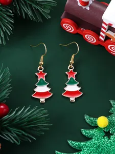 Detailed view of festive Christmas tree dangle earrings with colorful enamel on green background