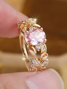 Macro shot of oval pink gemstone ring with intricate floral gold hollow band and diamonds