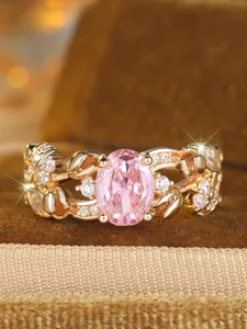 Detailed close-up of a vintage-style gold ring with oval pink gemstone and leaf accents
