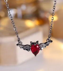 Makroaufnahme einer Gothic-Fledermauskette mit dunkelrotem Edelstein und schwarzen Flügeln