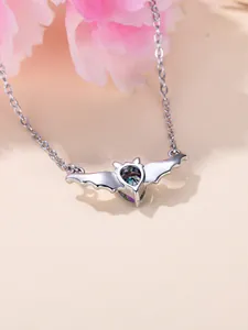 Nahaufnahme von Fledermaus-Anhänger mit schillerndem Herzstein und O-Kette in Silber