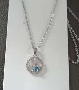 Macro view of silver snowflake pendant with a blue gemstone on a delicate cross chain