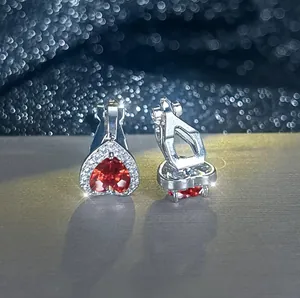 Vue macro de boucles d'oreilles clips coeur argenté avec pierre rouge et zircons