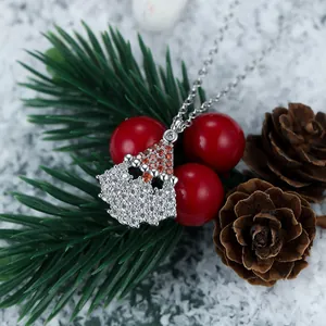 Macro detail of silver Santa Claus and hat pendant with zircon inlay on a festive background