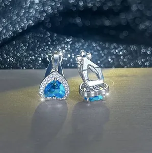 Vue macro des boucles d'oreilles clips en forme de cœur avec pierres bleues et argent