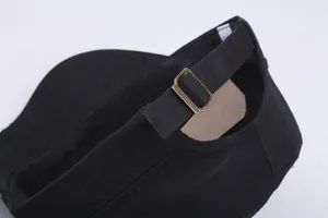Detail of adjustable metal buckle and cotton fabric texture on black flat top cap