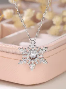 Macro shot of silver snowflake pendant with large sparkling crystal on pink jewelry box