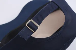 Detail of navy blue cotton flat top cap featuring adjustable brass metal buckle closure