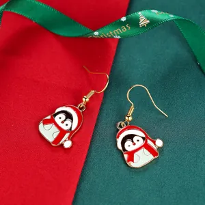 Christmas penguin drop earrings with red Santa hat and green scarf on holiday background