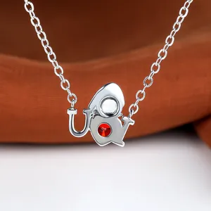 Close-up of silver necklace pendant featuring red gemstone and intricate metalwork