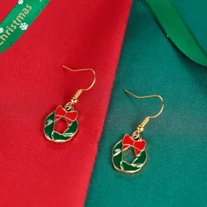 Christmas holly wreath earrings with red bows and gold hooks on festive fabric