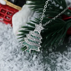 Macro detail of silver Christmas tree pendant featuring green crystals and snowy backdrop