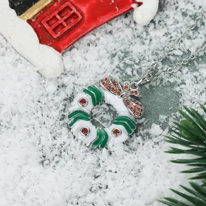 Christmas wreath pendant necklace with red bow and white enamel on festive snow background