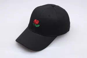 Close-up of the detailed red rose embroidery on a black cotton baseball cap with green leaves