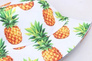 Gros plan de l'imprimé ananas sur chapeau bob blanc montrant texture et surpiqûres