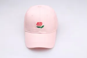 Close-up of a light pink baseball cap featuring detailed red rose flower embroidery