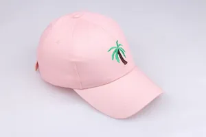 Close-up of coconut tree embroidery on a light pink cotton baseball cap with stitch detail