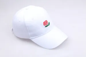 Close-up of white baseball cap with detailed red rose embroidery and curved brim