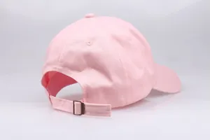 Detail view of pink cotton baseball cap with adjustable fabric strap and metal buckle