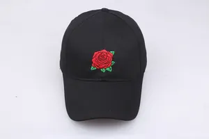 Close-up of red rose embroidery detail on black cotton baseball cap with green leaves