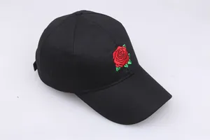Detailed close-up of red rose embroidery on a black cotton baseball cap with curved brim