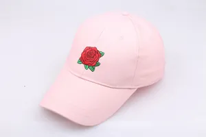 Close-up detail of red rose embroidery on a light pink cotton baseball cap with stitching
