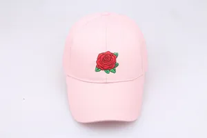 Close-up of a pink cotton baseball cap featuring detailed red rose floral embroidery