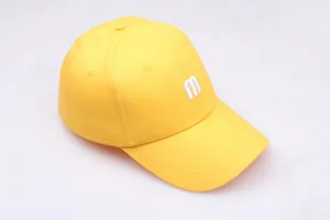 Vue détaillée de la casquette jaune en coton avec broderie de la lettre m en blanc