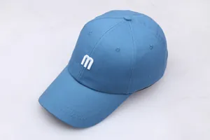 Détail de la casquette de baseball en coton bleu marine avec broderie 'm' et bord surpiqué