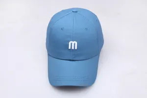 Vue détaillée de la broderie 'm' blanche sur une casquette de baseball en coton bleu