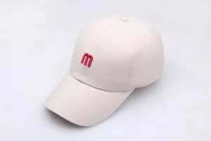 Gros plan sur la broderie de la lettre M rouge sur une casquette en coton beige avec coutures
