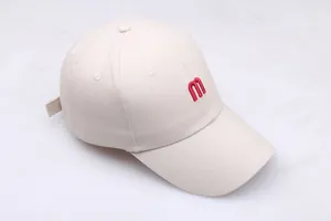 Gros plan de la broderie lettre M rouge sur casquette de baseball en coton beige