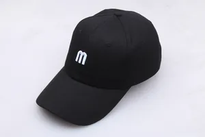 Gros plan sur la broderie de la lettre m blanche sur une casquette en coton noir sergé