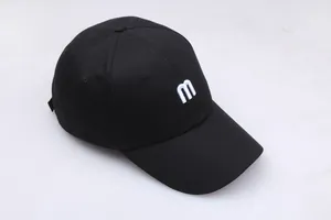 Gros plan sur la broderie fine de la lettre M blanche sur une casquette en coton noir