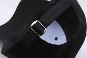 Détail de la casquette noire avec boucle en métal argenté et sangle réglable en coton