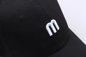 Gros plan sur la broderie 3D de la lettre M blanche sur une casquette en coton noir
