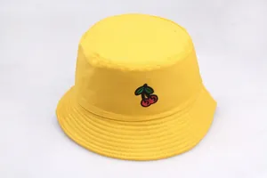 Detail of yellow canvas bucket hat featuring red cherry embroidery and reinforced stitching