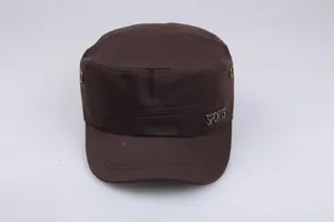 Detail view of cotton cadet cap in dark brown with metal sports emblem and side eyelets