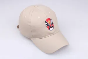 Detailed embroidery of Chinese Peking Opera mask on a beige cotton baseball cap surface