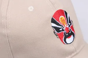 Macro detail of Peking Opera mask embroidery on khaki cotton baseball cap fabric