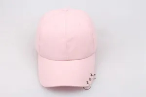 Detail of light pink baseball cap brim featuring three silver metal piercing rings décor